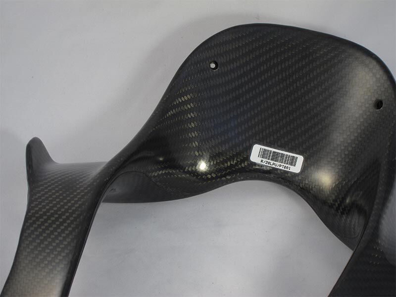 HANS device laying down on a white surface. The carbon fiber surface of the composite bladder molded structure is a weave with a glossy finish. This shows the head and one shoulder section.